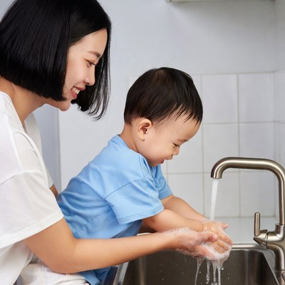 Asian mother helping toddler wash hands