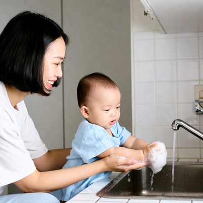 Asian mother helping baby wash hands