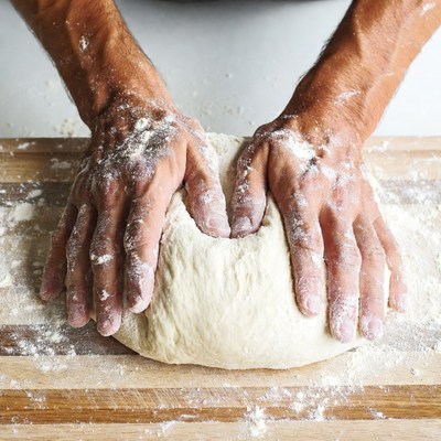 Man kneading dough on wooden board