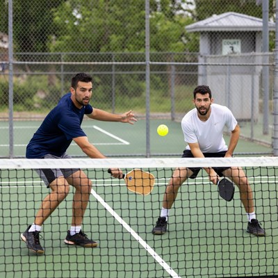 Two men playing pickleball over net
