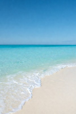 Turquoise waves crashing on white sand beach