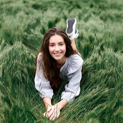Young woman lying in green grass field