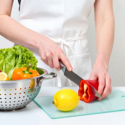 Woman chopping red pepper in apron