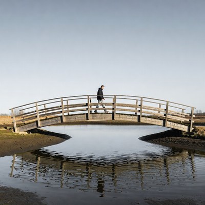 Man walking on wooden arched bridge