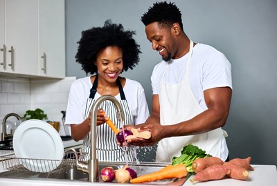 Black couple washing vegetables in kitchen