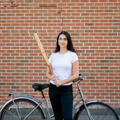 Woman with bat leaning on bicycle