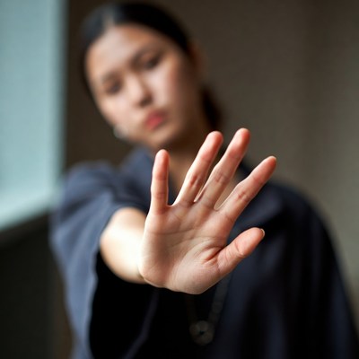 Asian woman raising hand to stop