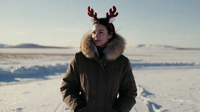 Woman with reindeer antlers in snowy field