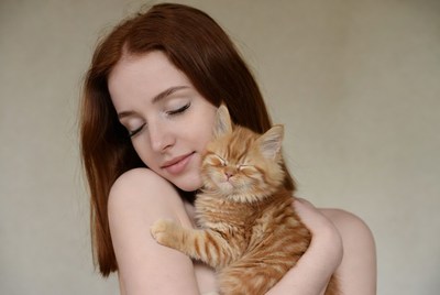 Redhead woman hugging orange kitten