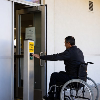Man in wheelchair using push button door