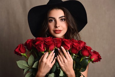 Woman holding red roses with black hat