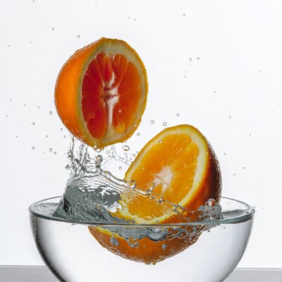 Sliced Oranges Splashing in Water Glass