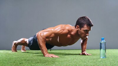 Muscular man doing pushups on grass