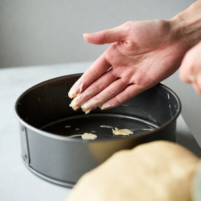 Woman greasing cake pan with butter