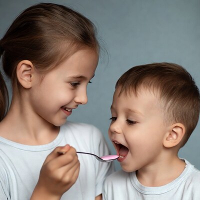 Girl feeding boy pink medicine