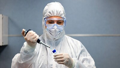 Woman pipetting sample in hazmat suit
