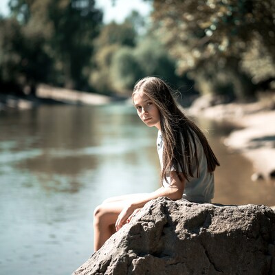 Girl sitting on rock by river