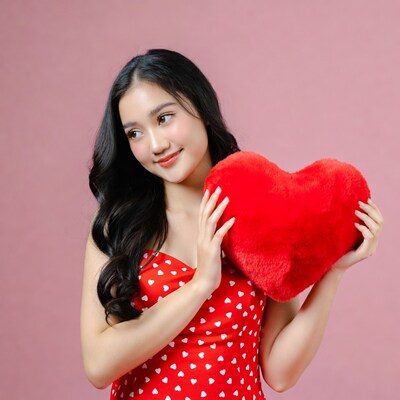 Asian woman holding red heart pillow