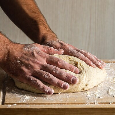 Man kneading dough on wooden board