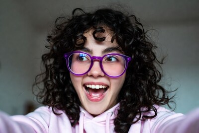 Smiling woman with curly hair and purple glasses