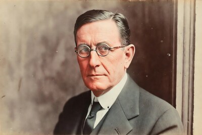 Elderly man in suit with round glasses