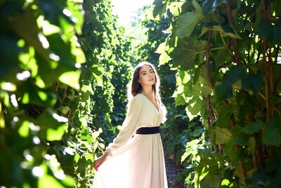 Woman in white dress in grapevine tunnel