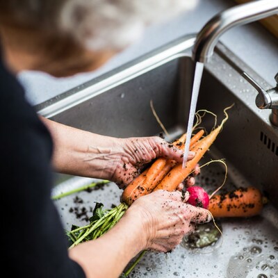 Elderly woman washing carrots sink