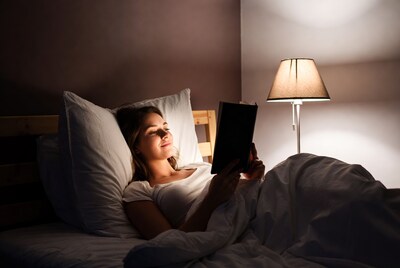 Woman reading book in bed at night