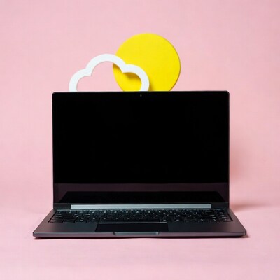 Laptop with cloud and sun on pink background