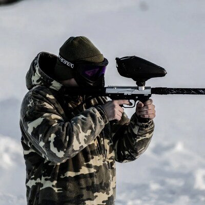 Man aiming paintball gun in snow