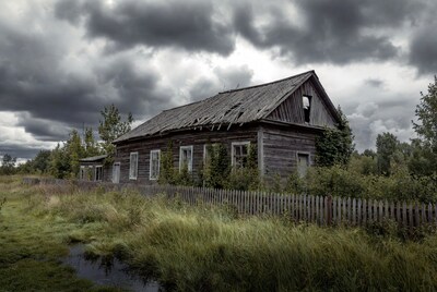 Abandoned wooden house under stormy sky