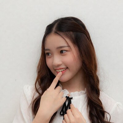 Asian woman pointing at lips smiling