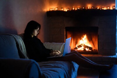 Woman using laptop by fireplace