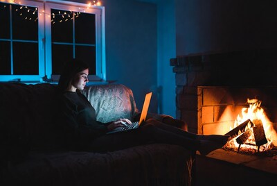 Woman working on laptop by fireplace