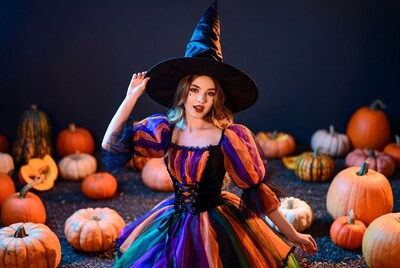 Woman in colorful witch costume with pumpkins