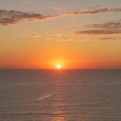Sunset over ocean with ship trail