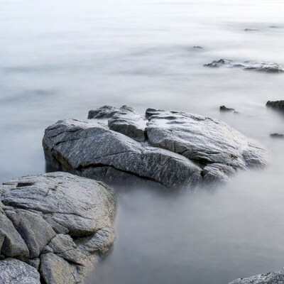 Rocks in foggy seashore water