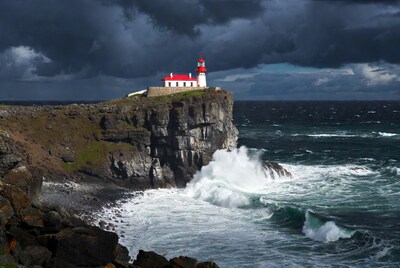 Red Lighthouse on Cliff Over Crashing Waves
