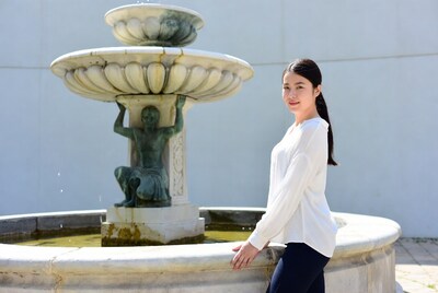 Asian woman leaning on stone fountain