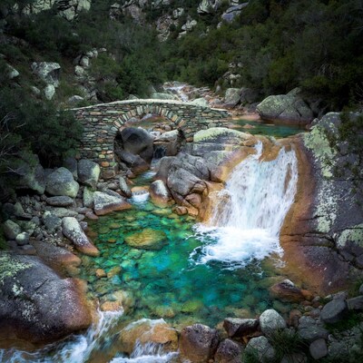 Stone Bridge over Turquoise Waterfall Pool