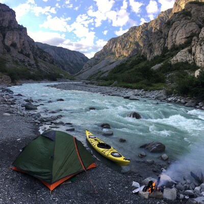 Green tent kayak campfire by mountain river
