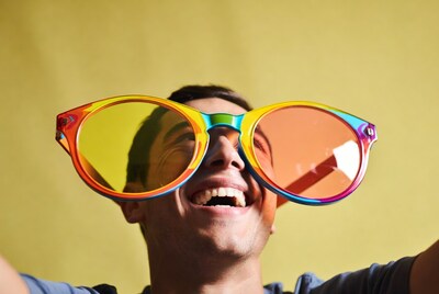 Man smiling in oversized rainbow sunglasses