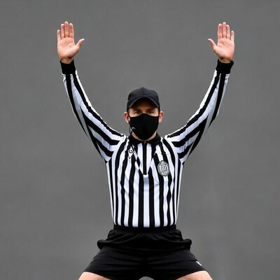 Referee raising arms wearing mask