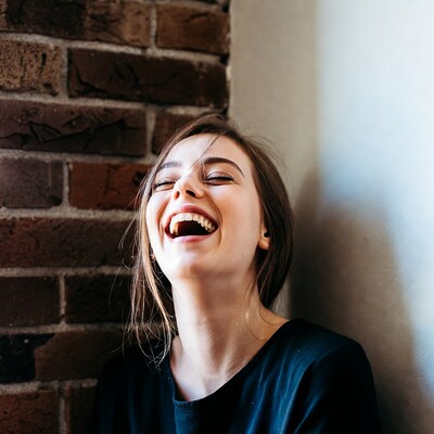 Woman laughing against brick wall