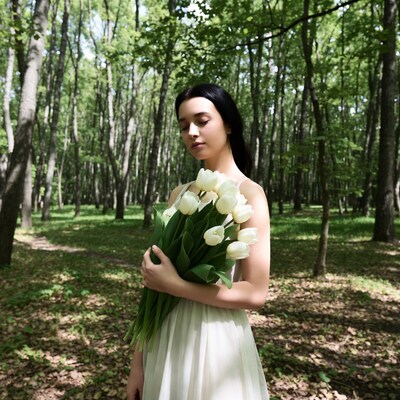 Woman holding white tulips in forest