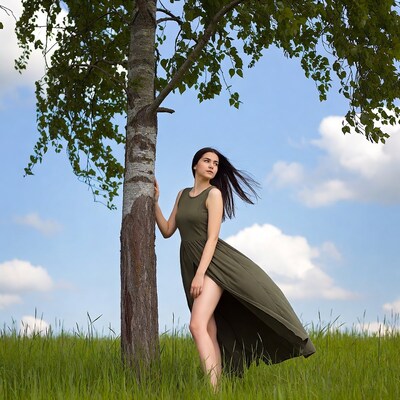 Woman leaning against tree in green dress