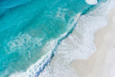 Turquoise waves crashing on white sand beach