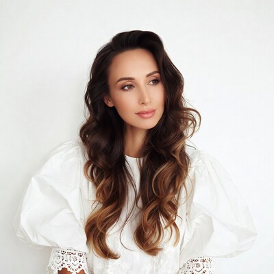 Woman with wavy brown hair in white blouse