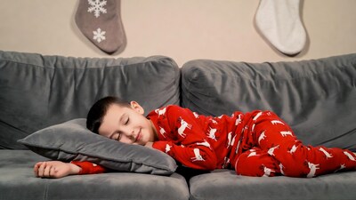 Boy sleeping in reindeer pajamas on couch