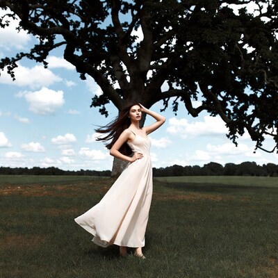 Woman in flowing dress by oak tree